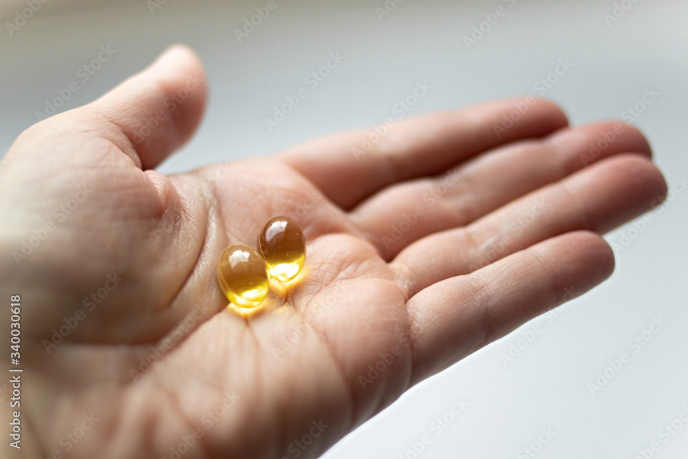 Close up omega 3 vitamin capsule in hand. capsule fish oil in hand. Useful supplement, healthy food Close up omega 3 vitamin capsule in hand. capsule fish oil in hand. Useful supplement, healthy food