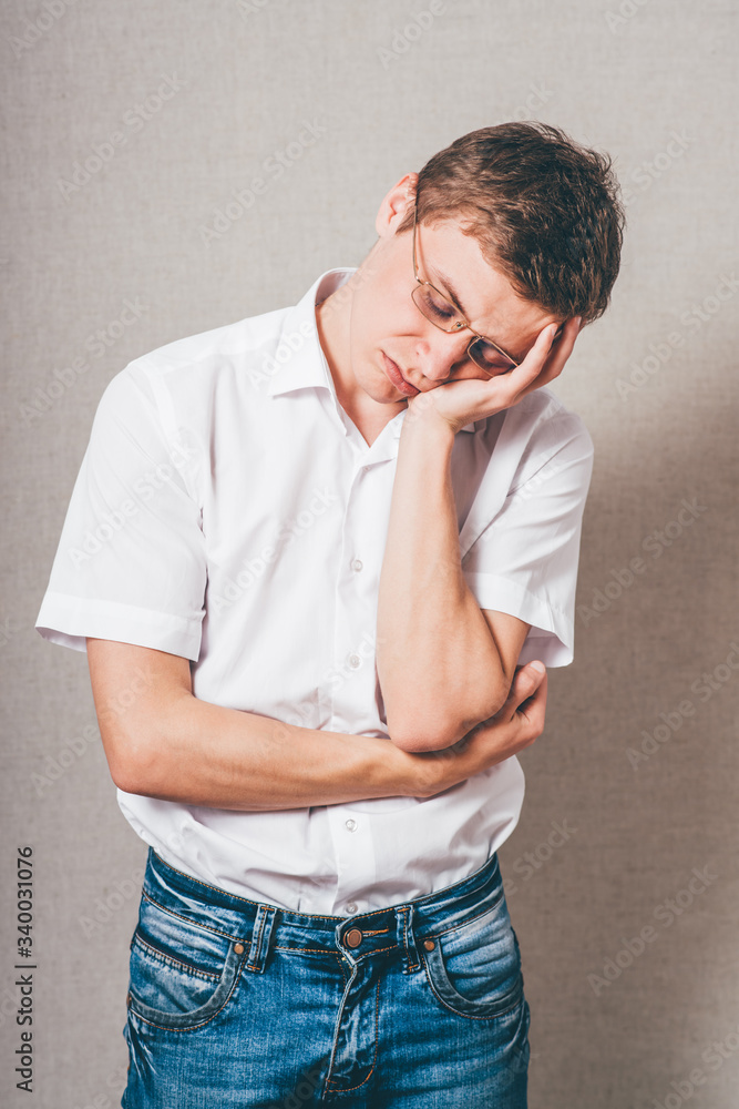 The man in glasses tired sleep. On a gray background. The man in glasses tired sleep. On a gray background.
