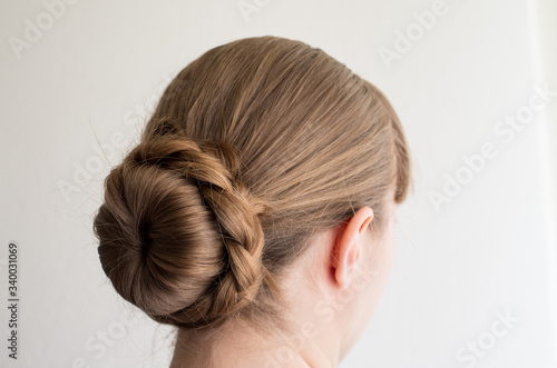 Caucasian young woman with her hair in a french bun with frizzy loose hairs seen from behind not recognizable