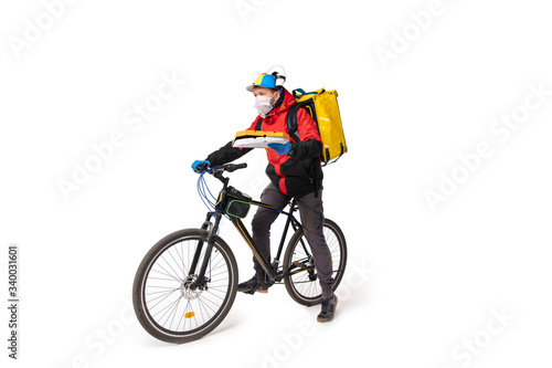 Fototapeta Naklejka Na Ścianę i Meble -  Too much orders. Contacless delivery service during quarantine. Man delivers food during isolation, wearing gloves and face mask. Taking pizza on bike isolated on white background. Safety. Hurrying up