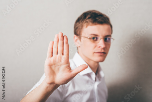 Male in glasses hand showing gesture stop timeout. On a gray background.