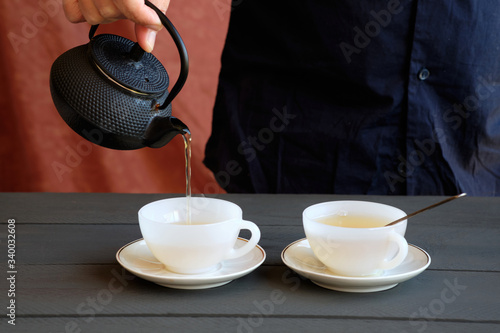 Man's hand serving two cups of green tea
