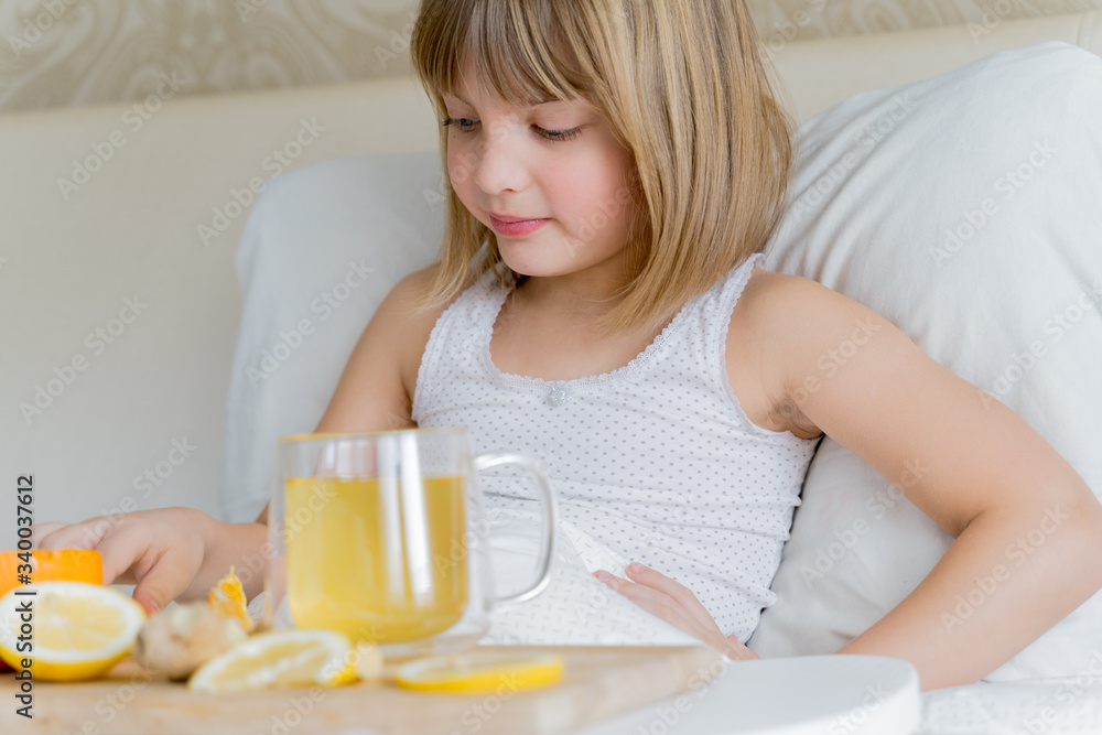 Little sick girl in bed with cup of antipyretic drugs for colds,flu.Tea with citrus vitamin C,ginger root,lemon,orange.Wooden tray. Home self-treatment.Medical quarantine covid-19 coronavirus therapy Little sick girl in bed with cup of antipyretic drugs for colds,flu.Tea with citrus vitamin C,ginger root,lemon,orange.Wooden tray. Home self-treatment.Medical quarantine covid-19 coronavirus therapy