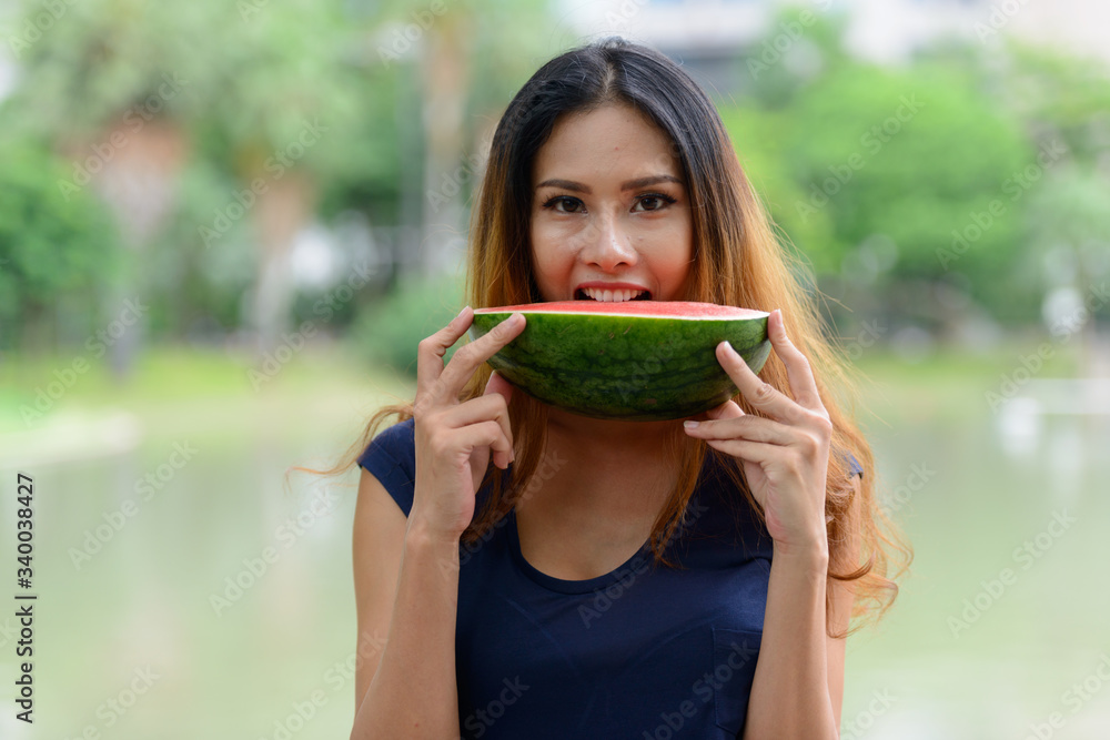 Happy young beautiful Asian woman eating watermelon at the park Happy young beautiful Asian woman eating watermelon at the park