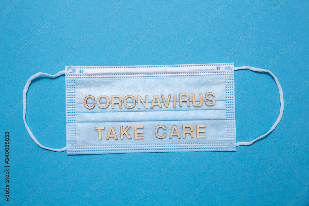 wooden letters CORONAVIRUS TAKE CARE on protective medical mask. Corona virus concept. wooden letters CORONAVIRUS TAKE CARE on protective medical mask. Corona virus concept.