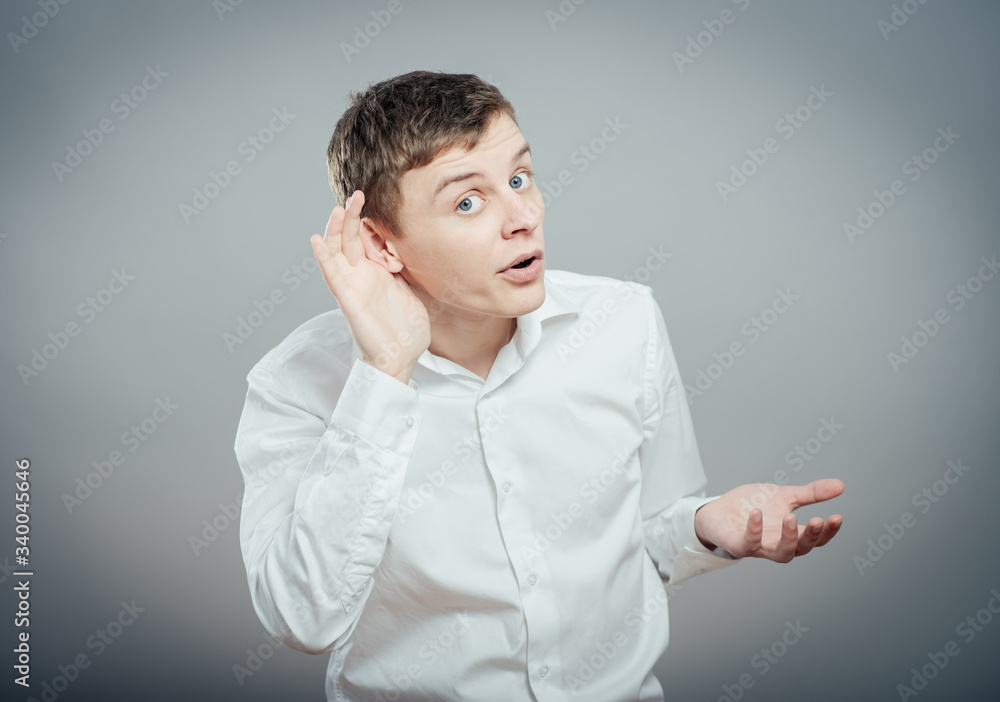 Closeup portrait of handsome young nosy business man secretly listening in on conversation, hand to ear, smiling at juicy gossip he hears, with smirk on face. Privacy Closeup portrait of handsome young nosy business man secretly listening in on conversation, hand to ear, smiling at juicy gossip he hears, with smirk on face. Privacy