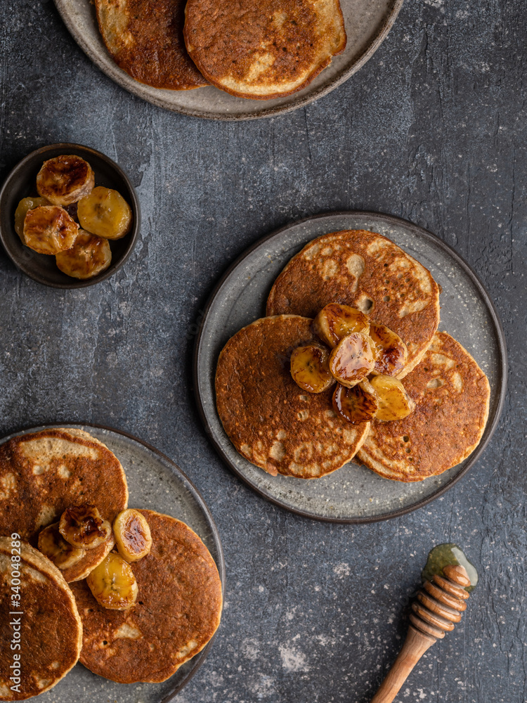 Oatmeal banana pancakes with honey and babana slices on ceramic plate. Healthy easy making morning breakfast. Homemade sugar free and gluten free food. Concrete background, top view. Copy space.
