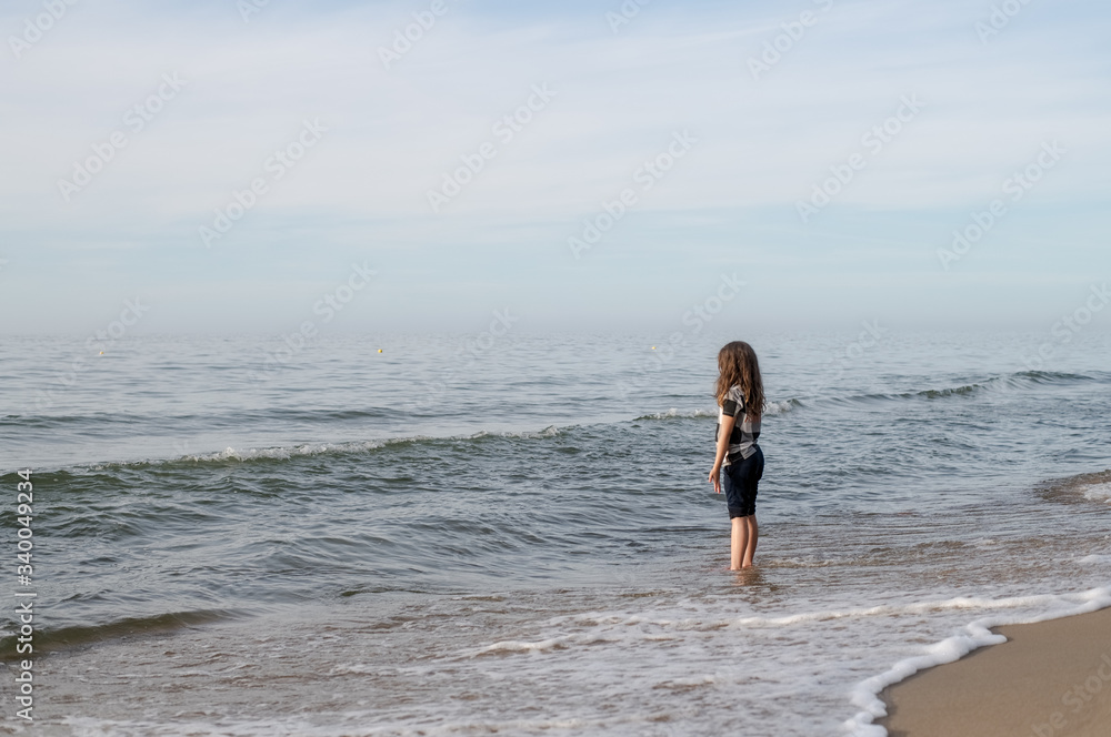 One long-haired girl running along the shore of the silver-colored North sea. Windy weather, Northern landscape, pastel color.