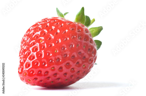 Fresh ripe red strawberry with green leaves on white background with dropped shadow. Studio shot