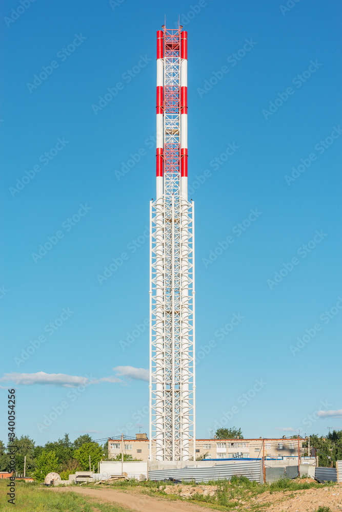 Obraz premium Metal chimney by the construction site at sunset time.