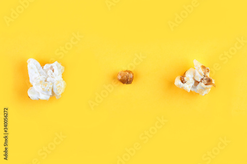 Caramel popcorn isolated on a yellow background, scattered. Mockup, frame of popcorn, top view.