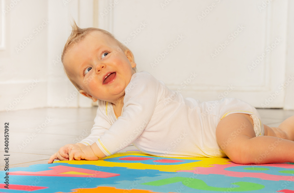Portrait of laughing happy face of toddler baby boy laying on the floor in nursery room looking back Portrait of laughing happy face of toddler baby boy laying on the floor in nursery room looking back