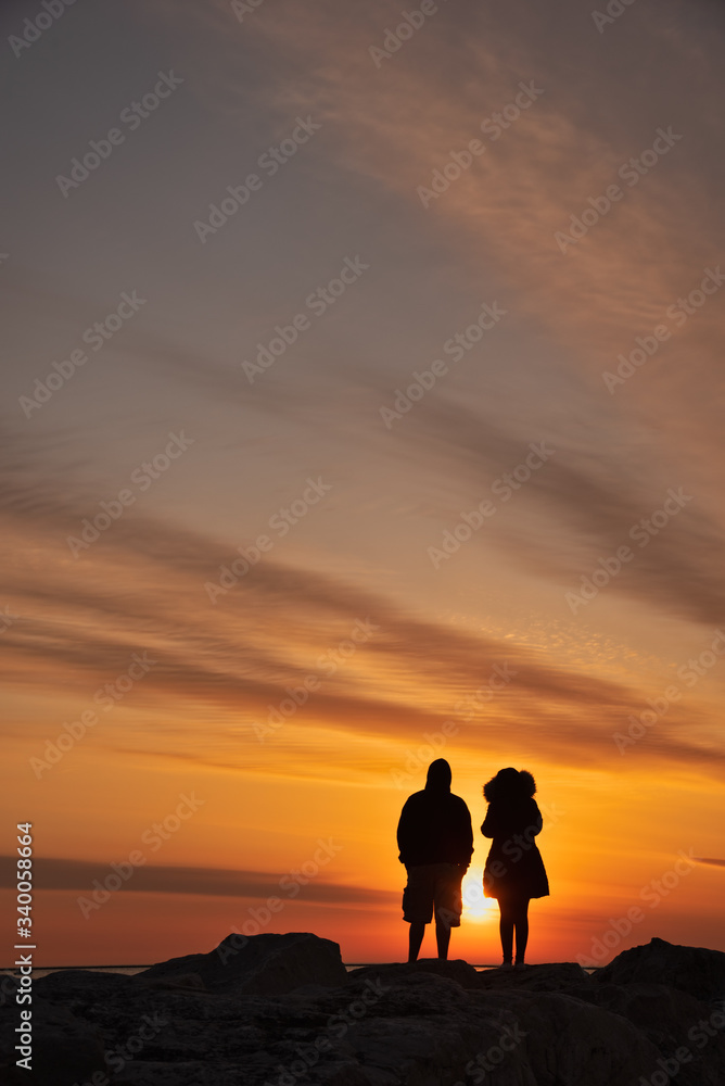 Alone together social distancing couple silhouette by the lake shore 