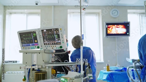 Modern equipment in the operating room in clinic. Medical workers look at the screen of a monnitor during robotic surgery. photo