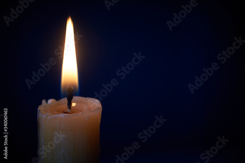 Close-up of white candle burning in the dark, candle fire on black background, selective focus