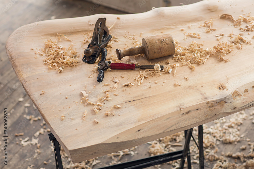 Obraz premium Wood shavings, wood curls and an old spokeshave on a wooden poplar table. Old carpentry tools