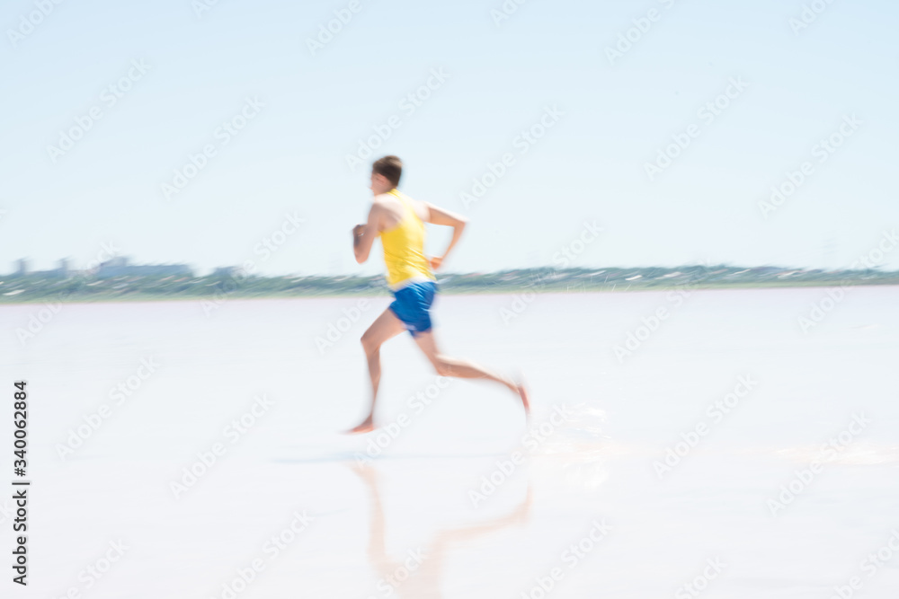 Young male runner running on a empty beach at dawn. Blur effect.