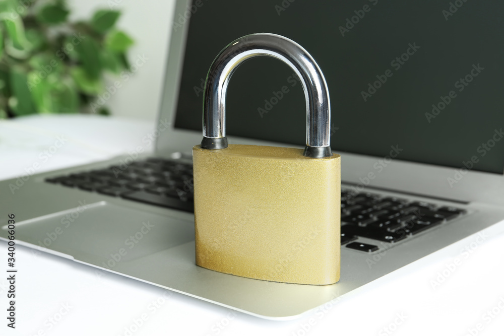 Metal lock and laptop on table, closeup. Protection from cyber attack Metal lock and laptop on table, closeup. Protection from cyber attack