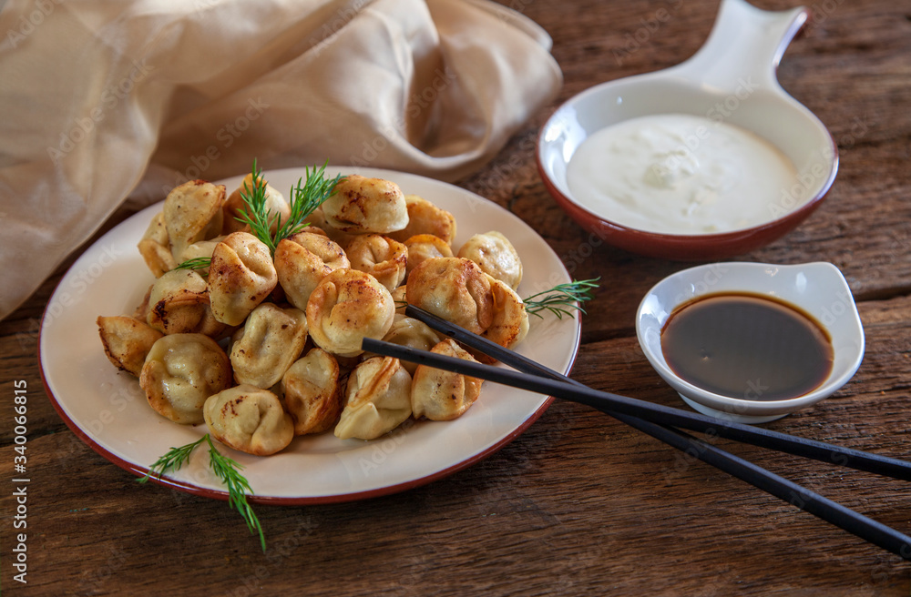 Dumplings with meat, onion and sour cream, on wooden background