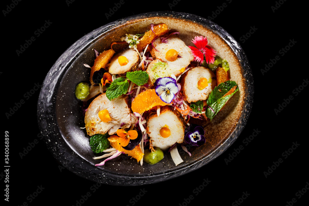 Mexican salad dish with sliced chicken mint leaves orange fresh pulps and flower decoration in black bowl. Appetizer photo in plain background best use for fine dine in restaurant menu. Mexican salad dish with sliced chicken mint leaves orange fresh pulps and flower decoration in black bowl. Appetizer photo in plain background best use for fine dine in restaurant menu.