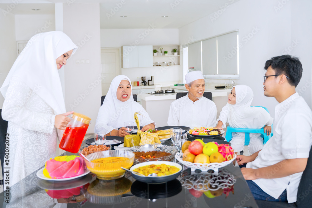Cheerful muslim family talk together in dining room
