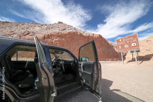 San Pedro de Atacama, Chile - Aug 13, 2015: Car with open doors in observation place, near San Pedro de Atacama, in front of a traffic sign indicating the Cordillera de la Sal (Salt Mountains).