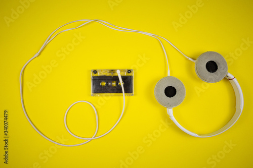 Audio cassette tape and modern headphones on a yellow background