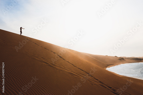 Silhouette of young woman standing on top of sand dune  punta gallinas  Colombia