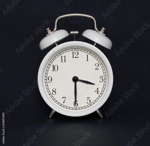 Old-style alarm clock, black and white, it's half past three.