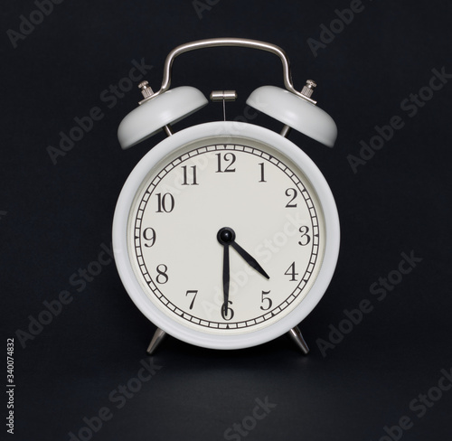Old-style alarm clock, black and white, it's half past four.