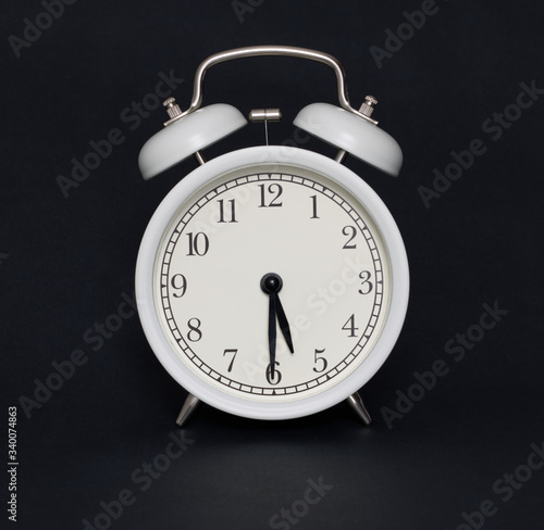 Old-style alarm clock, black and white, it's half past five.