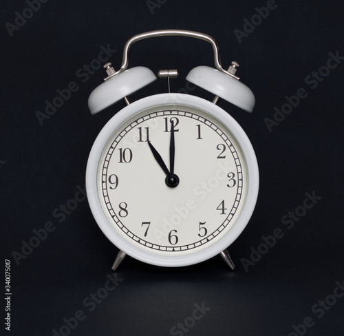Old-style alarm clock, black and white, it's eleven o'clock.