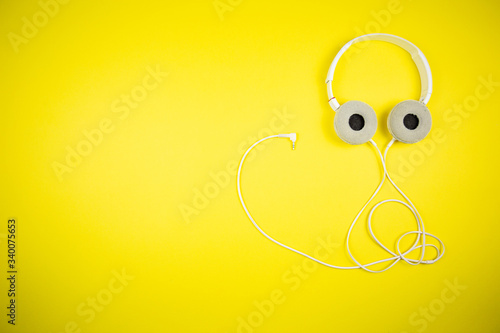 White audio headphones with a 3.5 mm wire on a yellow background

