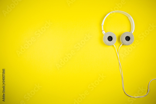 White audio headphones with a 3.5 mm wire on a yellow background 