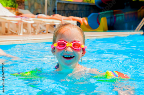 Very happy cute little child girl playing in the pool