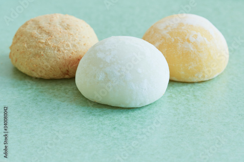 Closeup on three bright colorful mochis on a pastel green plate.