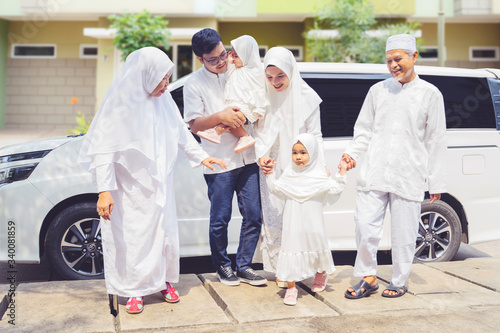 Happy muslim family walking together near the car