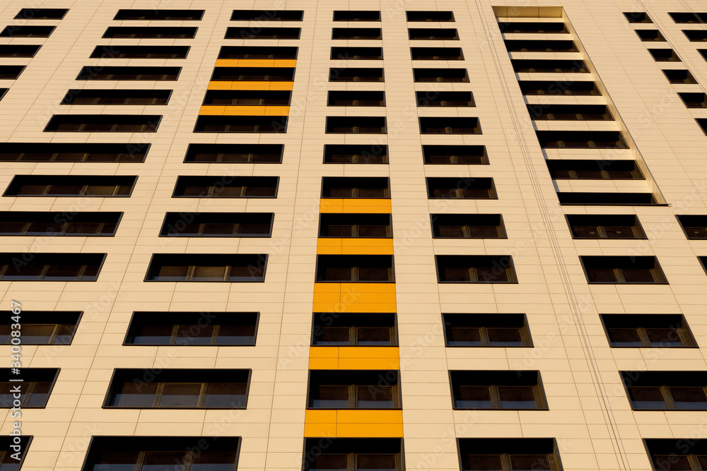 A row of windows on the ventilated facade of a typical modern residential building. Fragment of a new elite residential building or commercial complex. A row of windows on the ventilated facade of a typical modern residential building. Fragment of a new elite residential building or commercial complex.