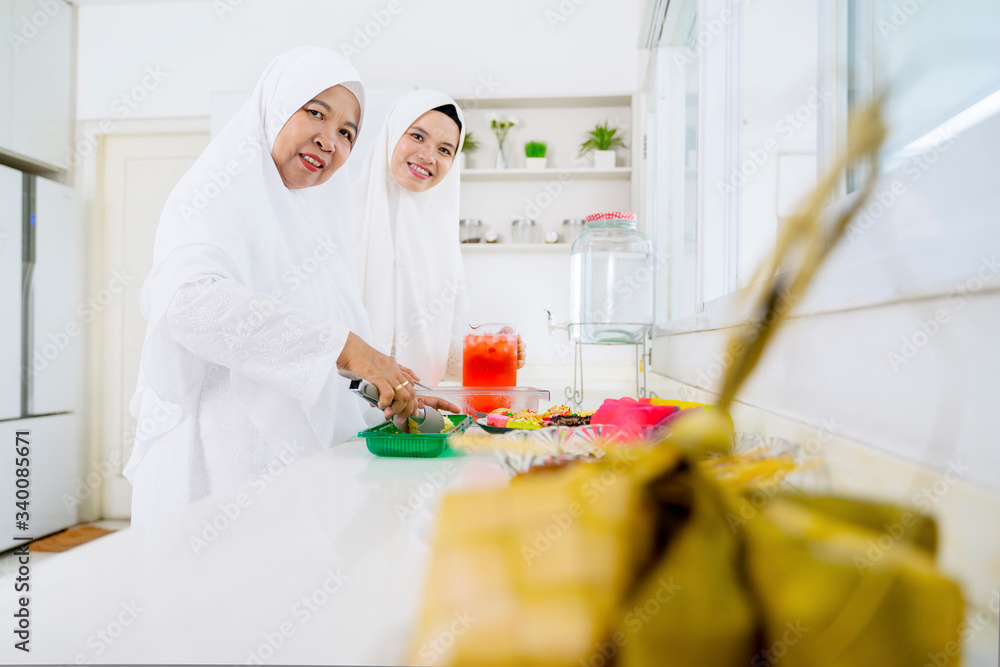 Muslim woman and her mother serving food and drink Muslim woman and her mother serving food and drink