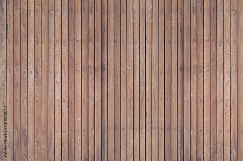 A solid wall of aged brown wooden planks with clogged nails located vertically. Concept for texture, background, interior.