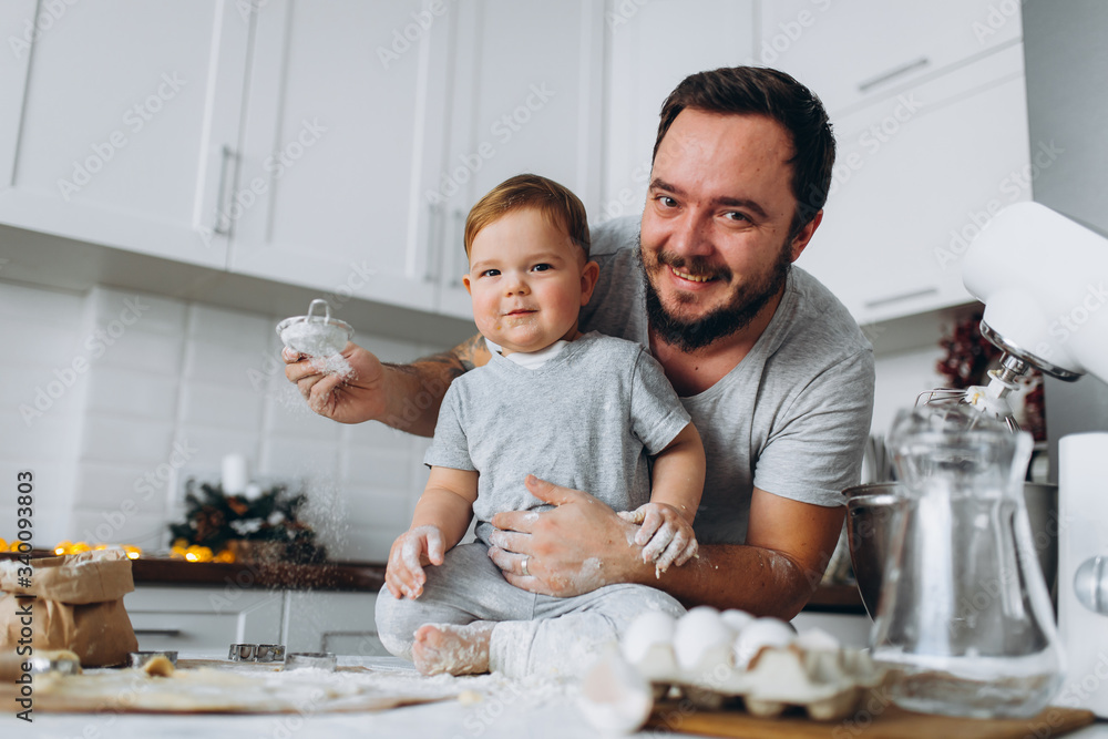 happy family in the kitchen. father and son preparing the dough, bake cookies happy family in the kitchen. father and son preparing the dough, bake cookies