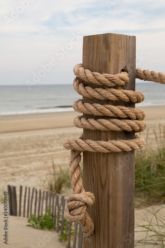 Rope Wrapped Around a Post in Front of Wild Grass and Short Barrier Fence with Crashing Waves on a Beach at Corolla, North Carolina