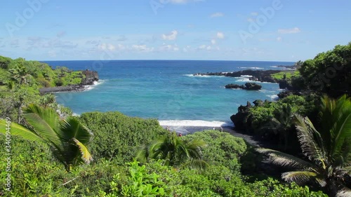 View of Pailoa Bay at Waianapanapa State Park on the drive to Hana on Maui with aqua ocean surrounded by jagged lava rock with black sand beach below on sunny blue-sky Hawaii day. photo