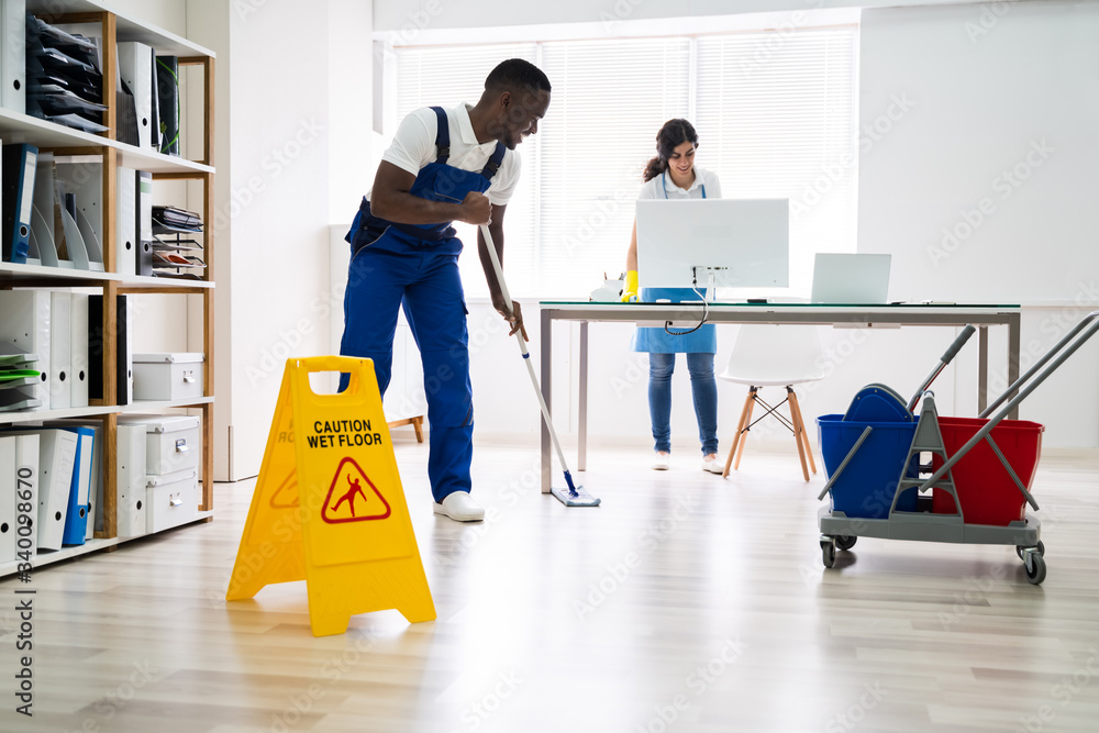 Obraz premium Male And Female Cleaners Cleaning Office