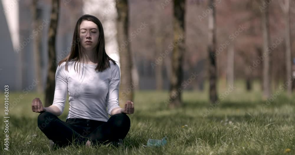 Attractive woman with medical mask on meditating in nature Attractive woman with medical mask on meditating in nature