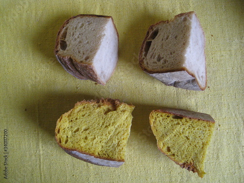 piezas de pan , 4, forma de cuña,  dos de trigo y dos de maíz, vista cenital, comparación de migas, cortadas de hogaza de pan de pueblo de horno artesano,  color crema, grisáceo y amarillo, sobre tela photo