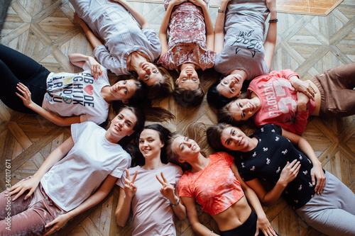 Top view of nine happy beautiful women laying on the floor.