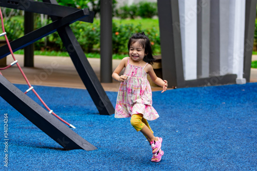 Cute little asian kid girl while running and enjoying on a playground