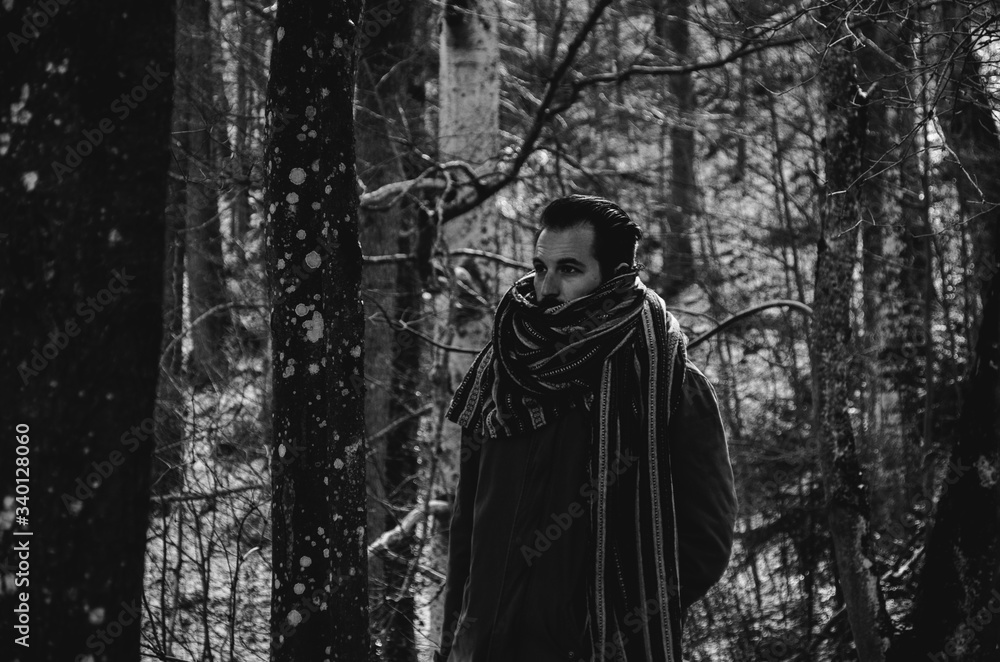 Black and white young man in a forest wearing a scarf