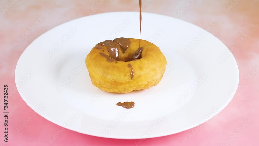 Pouring chocolate on delicious donuts in white plate Pouring chocolate on delicious donuts in white plate